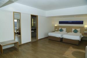 a hotel room with two beds and a mirror at Sarovar Portico Rivera Ahmedabad in Ahmedabad