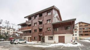 a large wooden building with a car parked in a parking lot at Alpina Lodge 23 - Appt pied des pistes 6 pers in Les Deux Alpes