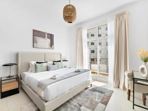a white bedroom with a large bed and a window at Stunning and Brand New La Fontana 513 in Dubai