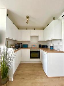 une cuisine blanche avec des armoires blanches et une plante en pot dans l'établissement 288 Belle Aire, Hemsby - Beautifully presented two bed chalet with veranda, sleeps 5, pet friendly, free Wi-Fi, bed linen and towels included and onsite entertainment available, à Hemsby