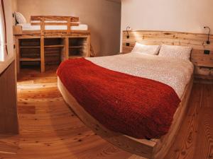 a bedroom with a large bed with a red blanket at B&B Maso Ghirola in Pinzolo