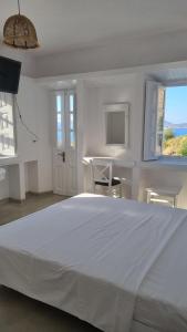 een witte slaapkamer met een groot bed en een raam bij Eirini Residences in Sapsila