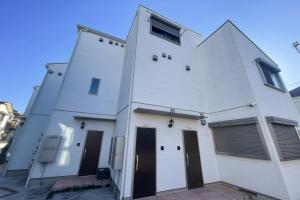 a white building with two doors and two windows at YIAN-Kamiochiai house in Tokyo