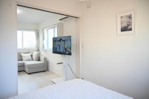 a white living room with a tv on a wall at YIAN-Kamiochiai house in Tokyo
