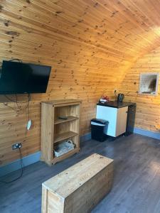 a room with a tv in a wooden cabin at Original Glamping Pod with Hot Tub in Frodsham