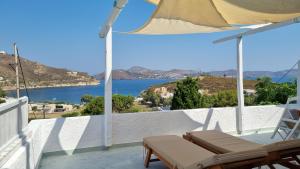 een balkon met stoelen en een parasol en de oceaan bij Eirini Residences in Sapsila