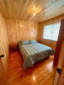 1 dormitorio con 1 cama en una habitación de madera en Cabañas Vista al Mar en Valdivia