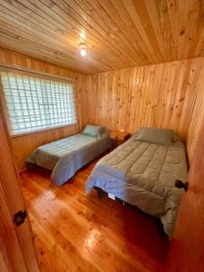 a bedroom with two beds in a wooden cabin at Cabañas Vista al Mar in Valdivia