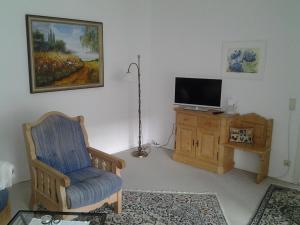 un salon avec une chaise et une télévision dans l'établissement Ferienwohnung Christa Hahn, à Birkenau