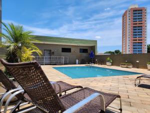a swimming pool with two chairs next to a building at Carlton Plaza São José dos Campos in São José dos Campos