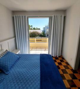 1 dormitorio con cama azul y ventana grande en Casa de praia em Florianópolis, en Florianópolis