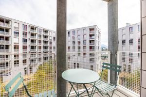 a table and chairs on a balcony with buildings at Nidfeld by Coliving in Lucerne
