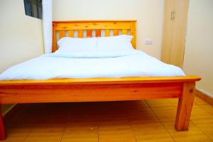 a wooden bed with white sheets on top of it at SAGE Apartments-South B in Nairobi