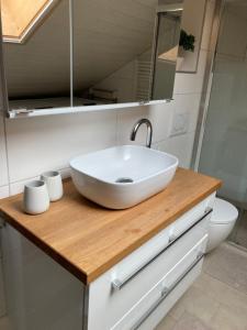 ein Badezimmer mit einem weißen Waschbecken auf einer Holztheke in der Unterkunft "La Petite Rochette" in Estavayer-le-Lac