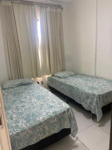a bedroom with two beds and a window at Apartamento bossa nova in Aracaju