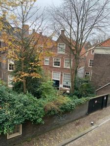 un bâtiment avec des arbres et des buissons en face d'une rue dans l'établissement Galerie Petit Delfshaven, à Rotterdam