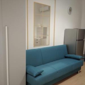 Cette chambre comprend un canapé bleu et un réfrigérateur. dans l'établissement Bell'House Milazzo, à Milazzo