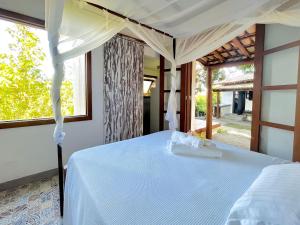 una camera da letto con un letto bianco con baldacchino di Casa com piscina e vista para a Praia do Espelho a Porto Seguro Altre 45 foto