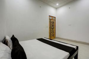 a bedroom with a white bed with a wooden door at OYO 82103 Royal guest house in Morādābād