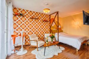 a bedroom with a bed and a chair and a table at Suite année 70 - Jacuzzi et Balcon in Caen