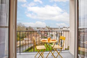 a table and chairs on a balcony with a view at Suite année 70 - Balnéo et balcon in Caen