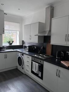 a kitchen with white cabinets and a stove top oven at Guest Homes - Driffield Apartment in Great Driffield