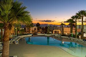 - une piscine avec des chaises et des palmiers dans un complexe dans l'établissement Apartamentos Panorama Adults Only, à Puerto del Carmen