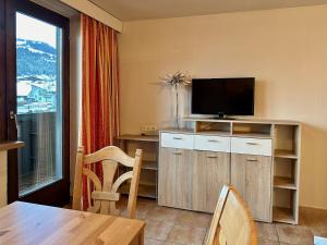 - un salon avec une télévision et une table à manger dans l'établissement Apartments Max & Moritz, à Kirchberg in Tirol