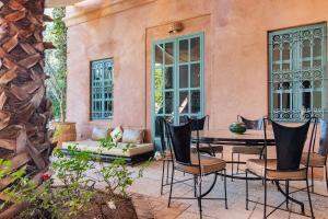 een patio met stoelen en een tafel voor een gebouw bij Villa Pauline with private pool & garden, hotel service and no insight. in Marrakesh