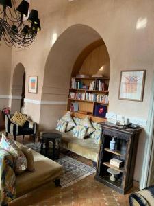 Villa Pauline with private pool & garden, hotel service and no insight. في مراكش: غرفة معيشة مع أريكة ورف كتاب