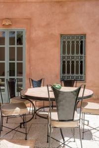 une table et des chaises devant un bâtiment dans l'établissement Villa Pauline with private pool & garden, hotel service and no insight., à Marrakech