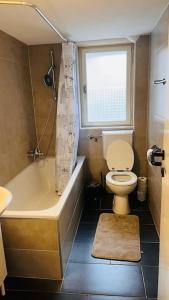 a bathroom with a toilet and a tub and a window at Cresta Apartment in St. Gallen