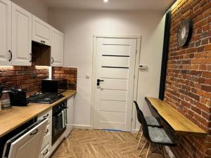 a kitchen with white cabinets and a brick wall at Lusia Apartment in Jarosław