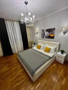 Un dormitorio con una cama grande y una lámpara de araña. en Апартаменты MOON APARTMENTS - ZENKOVA 86, en Almaty