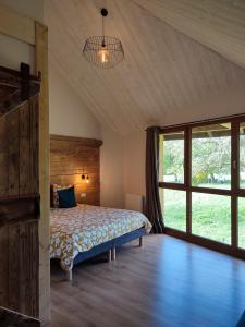een slaapkamer met een bed en een groot raam bij Le Grenier - Chambre d'hôtes 