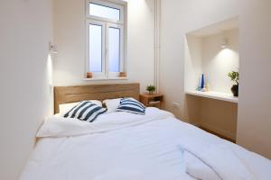 a bedroom with a white bed with blue and white pillows at Porta Apartments Novi Sad in Novi Sad