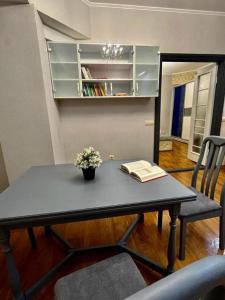 Una mesa negra con un libro y flores. en Апартаменты MOON APARTMENTS - ZENKOVA 86, en Almaty