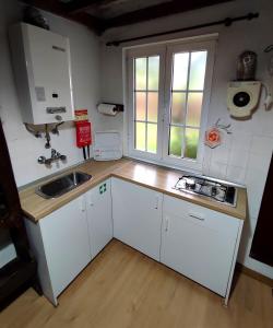a small kitchen with white cabinets and a sink at Casa do Limoeiro 1 in Valezim