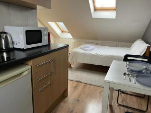 a kitchen with a microwave and a room with a bed at Private Studio Room With Your Shower and Kitchen in London