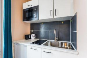 eine kleine Küche mit einer Spüle und einer Mikrowelle in der Unterkunft CMG - Résidence Edouard Vaillant in Pantin