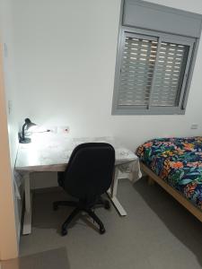 a desk with a chair in a room with a bed at Lovely room at Benny's apartment in Netivot
