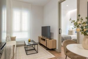 een woonkamer met een televisie op een houten kast bij 2 single beds in Chamberi Quevedo III in Madrid
