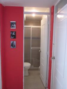 uma casa de banho com um WC e uma parede vermelha em Apartamento terrazas de cajica em Cajicá