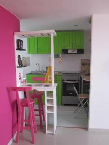a kitchen with green cabinets and a table with stools at Apartamento terrazas de cajica in Cajicá