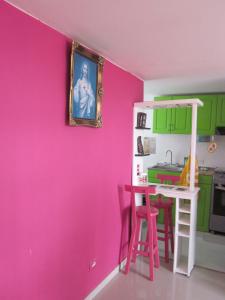 uma cozinha com uma parede rosa e uma mesa com bancos em Apartamento terrazas de cajica em Cajicá