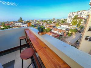 a balcony with a wooden bench and stools at Fefe's home in Dar es Salaam