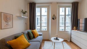 a living room with a couch and two windows at Cœur de Fontainebleau: Confort, Calme & Haut débit in Fontainebleau