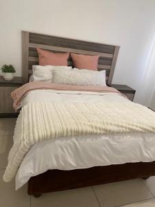 un grande letto con lenzuola e cuscini rosa e bianchi di Makyle's Selfcatering Apartment a Windhoek