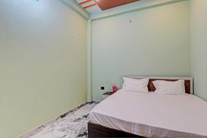 a bedroom with a large bed with white sheets at OYO Green Valley Guest House in Sultānpur