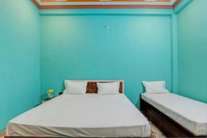 two beds in a room with a blue wall at OYO Green Valley Guest House in Sultānpur